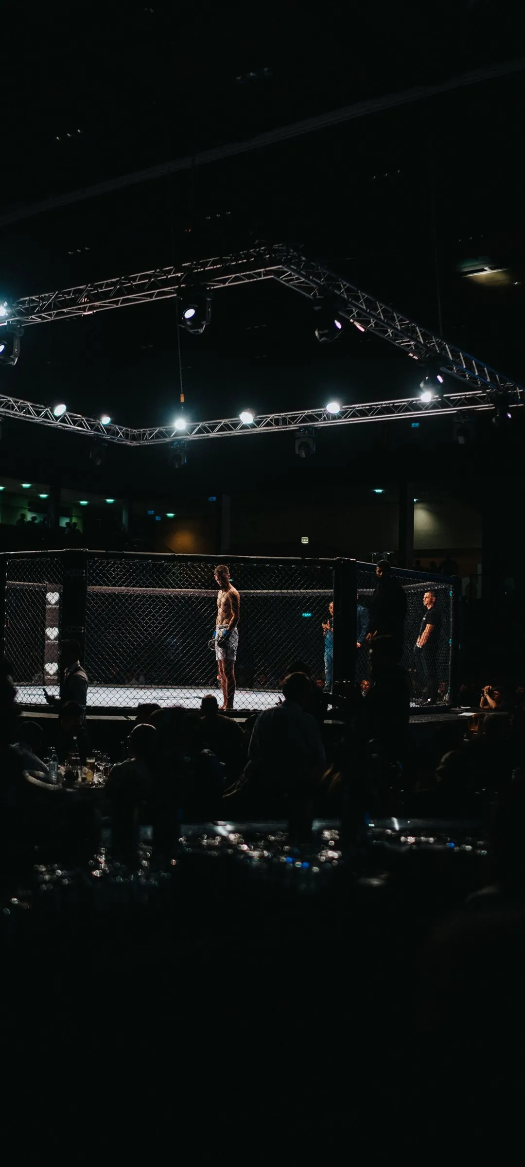 A fighter standing in a lit cage before a bout